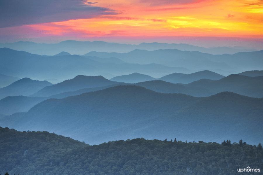 Mountain view of Asheville North Carolina at sunset with mountains trees and a pink/yellow sky