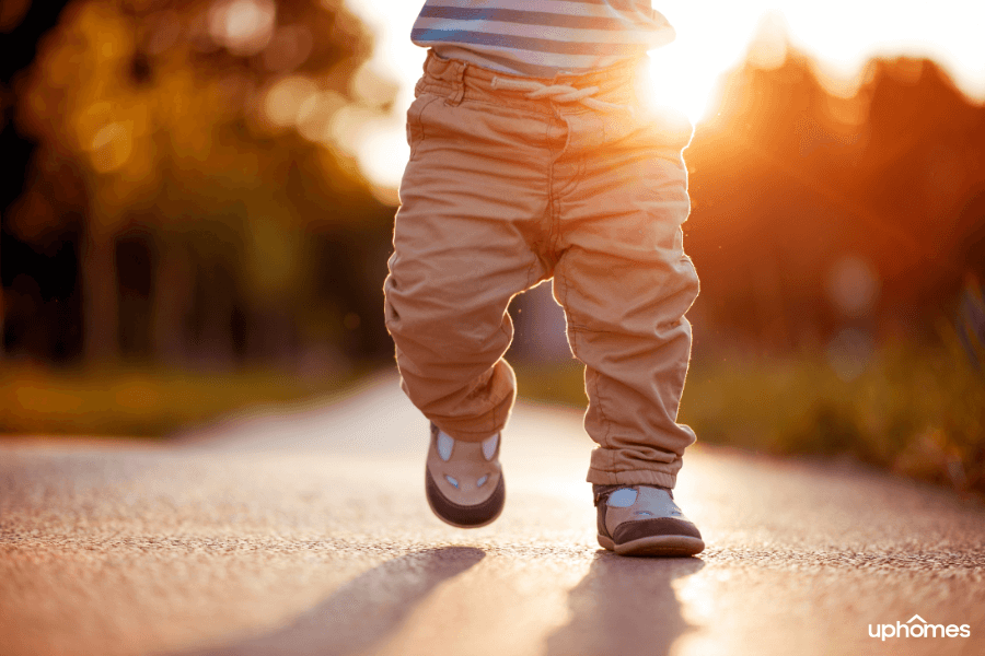 A close up of shoes and Baby walking down the street towards home while the sun is setting