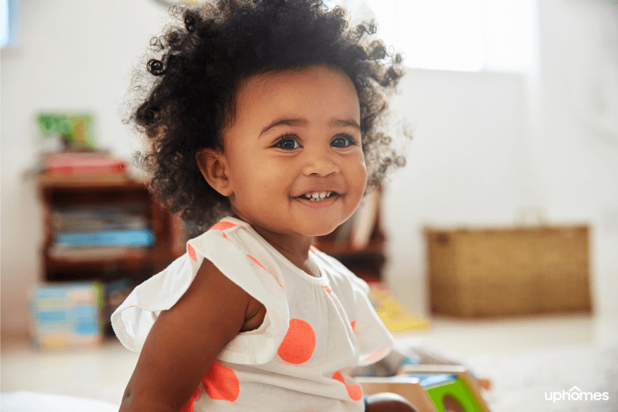 Black newborn baby with toys in the background laughing and smiling