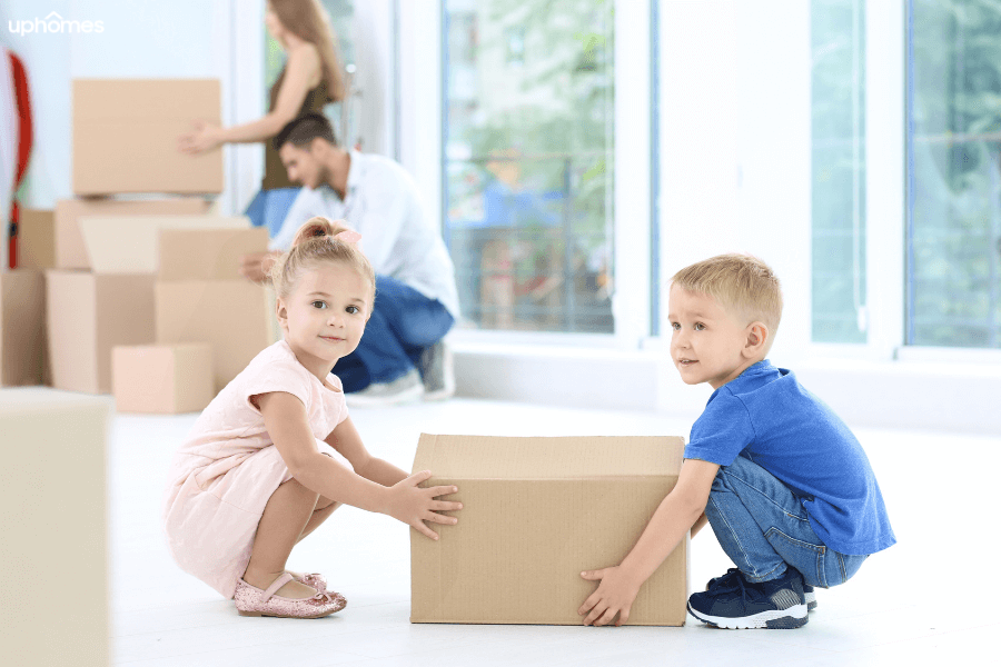 Children helping with the moving boxes as family moves to a new home giving the kids a sense of value and importance in the move