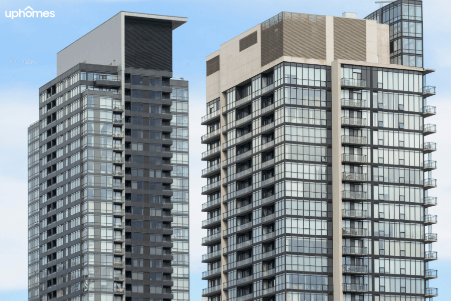 Two condo buildings next to one another with a bunch of condominium units for sale overlooking the ocean and a blue sky