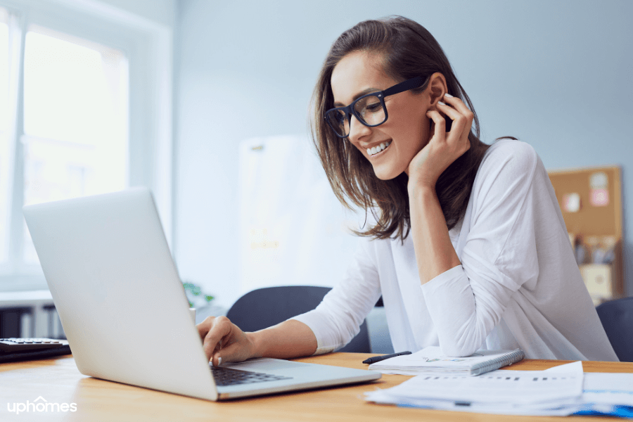 Girl working in her home office with glasses on and great lighting with a big smile on her face