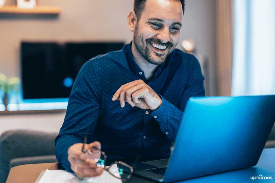 Home Office Worker from home with a big smile on his face while holding his glasses in his hand