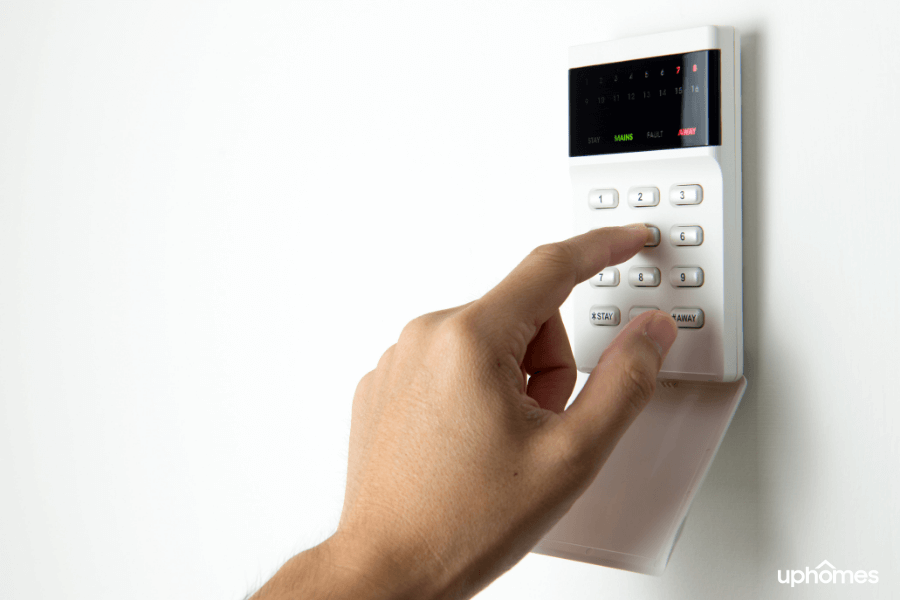 A photo of a home security system alarmed and ready to go with a finger typing in the code to protect the home in the event of a burglary or even carbon monoxide