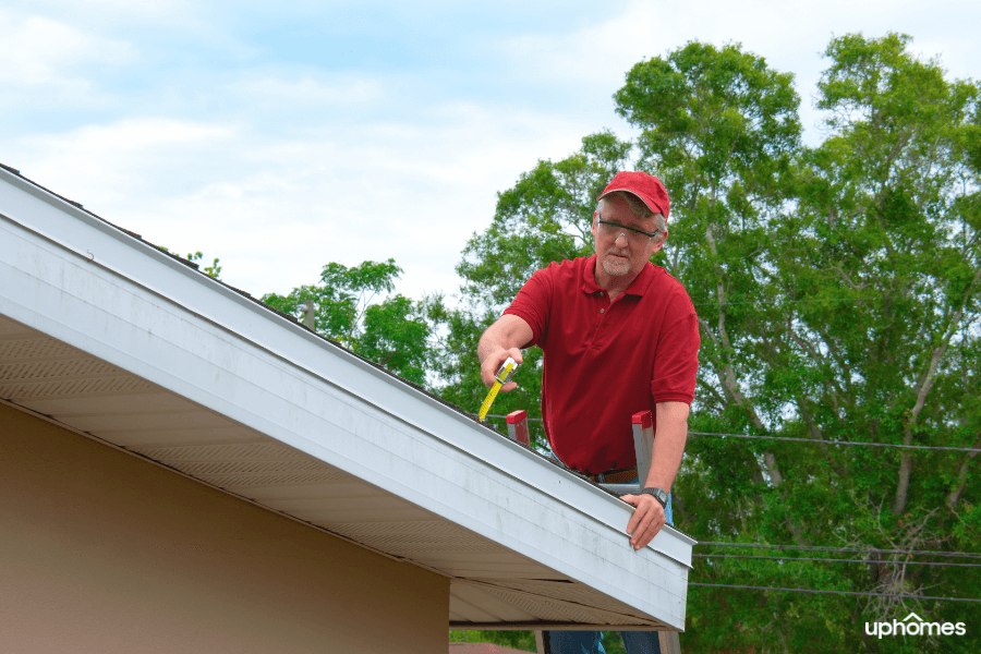 Home Inspector up on the roof with a tape measure making sure the roof is safe for the new homeowners and passes inspection
