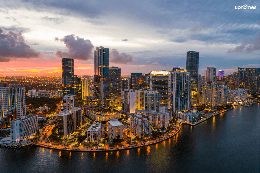 Miami city skyline at sunset with water in the foreground and the sun setting in the background