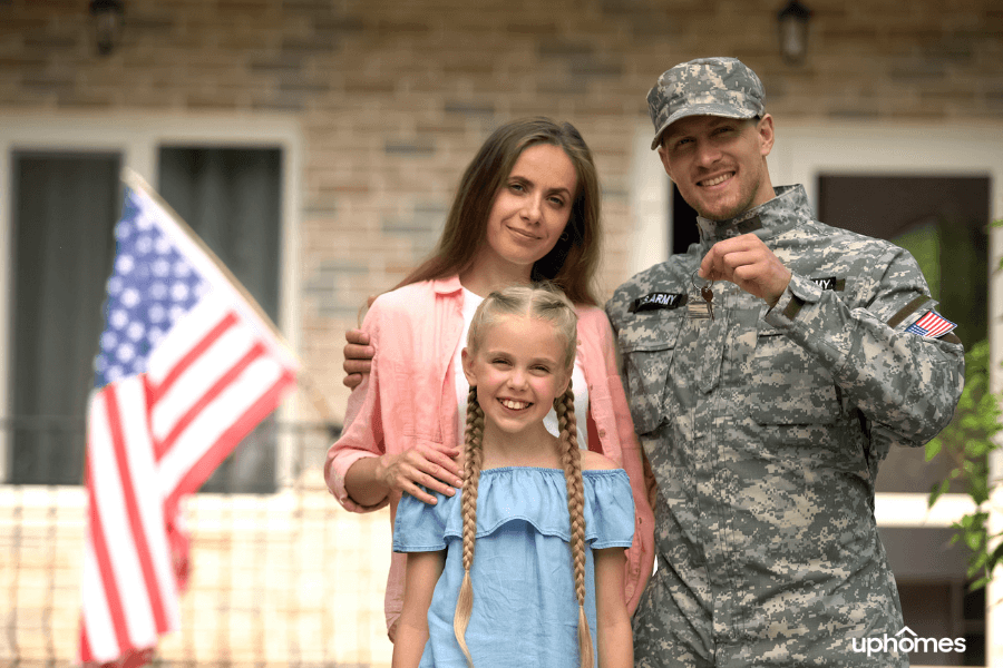 Military family moving to new home with active duty father holdings keys in hand with a happy daughter and mom