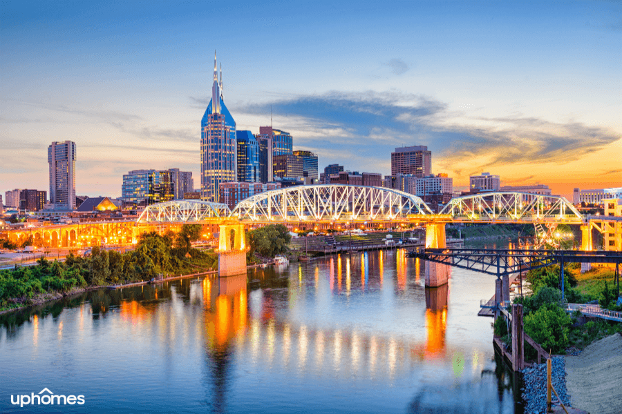 A photo of Nashville Tennessee that displays the downtown skyline, the water and bridge at sunset