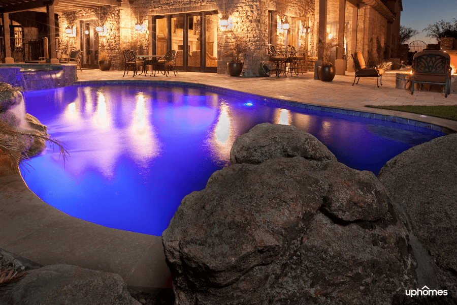 A backyard complete with stonework and a pool with great lighting and a serene backyard setting