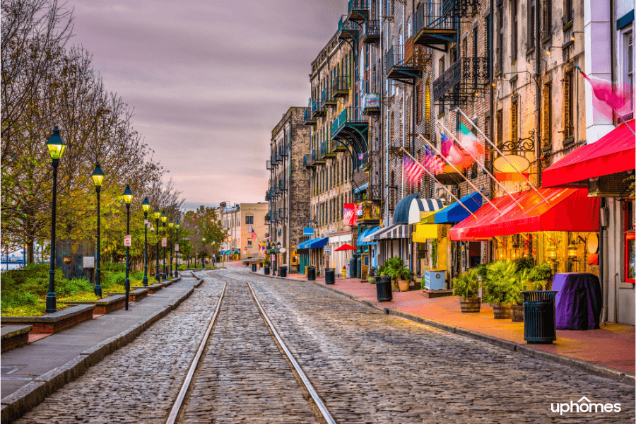 Savannah GA downtown shops and cobblestone pavement with a train track in a night time setting