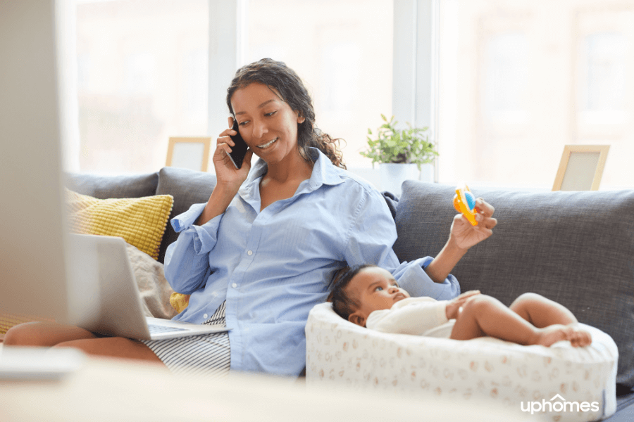 Single Mom working hard while looking at homes on the computer, talking on the phone and taking care of son in the background