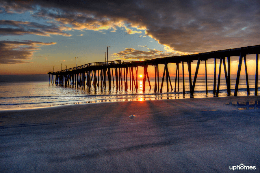 Beach in Virginia with the sun setting in the background and the sand and water in the foreground