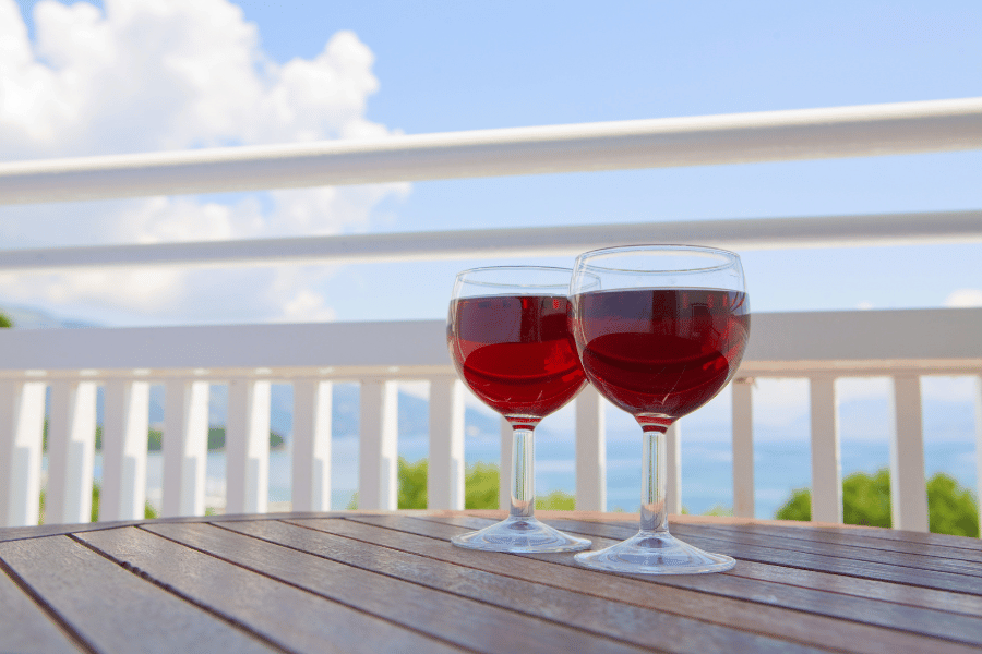 two glasses of wine on a patio overlooking the beach