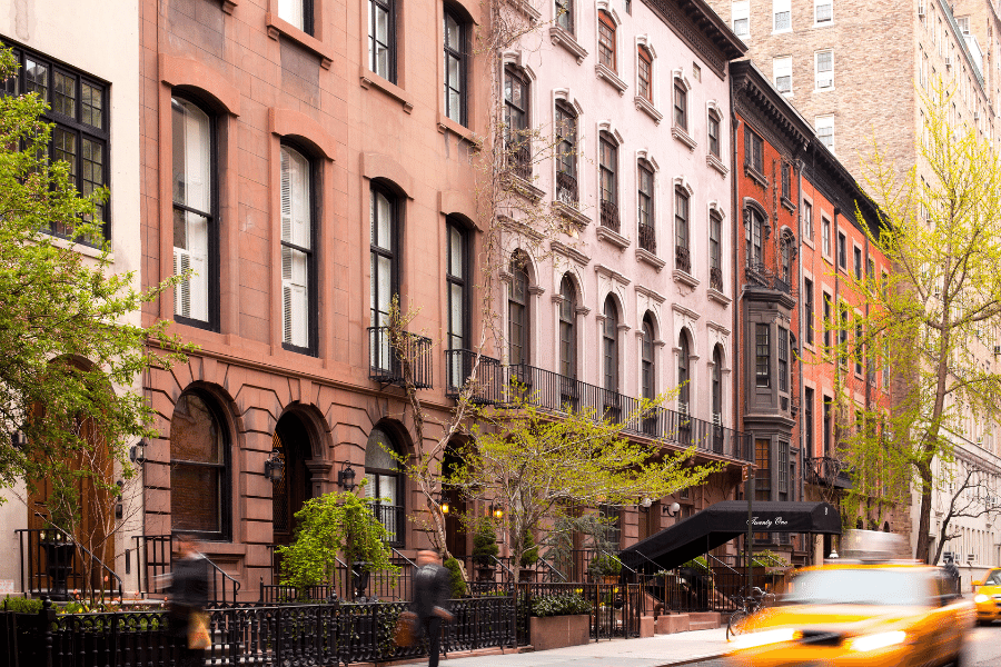 Beautiful brownstones in Queens, NY and taxis driving by on the street