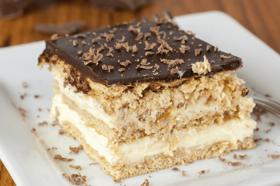 slice of Boston creme pie on a white plate with chocolate shavings 