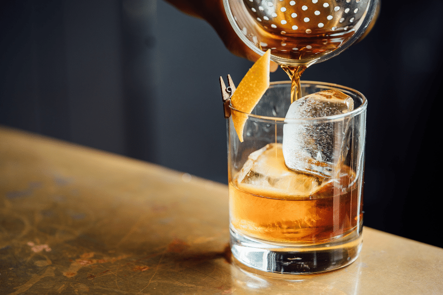 Pouring a cocktail drink in a glass with ice 