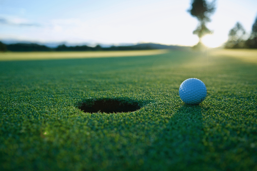 golf ball sitting next to the hole on a golf course green