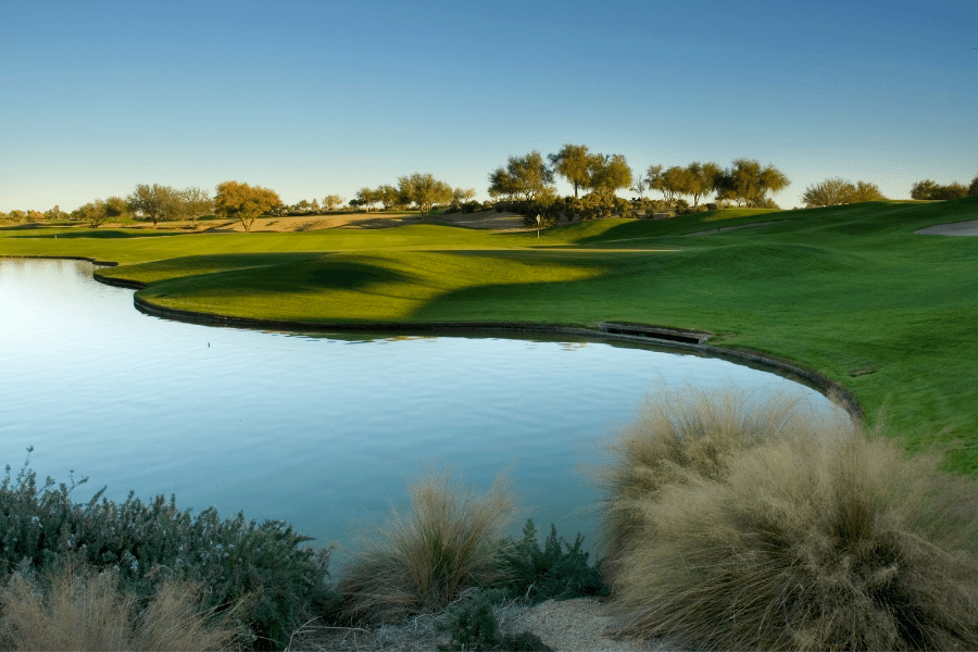 A beautiful golf course with a clear blue lake and green fairway