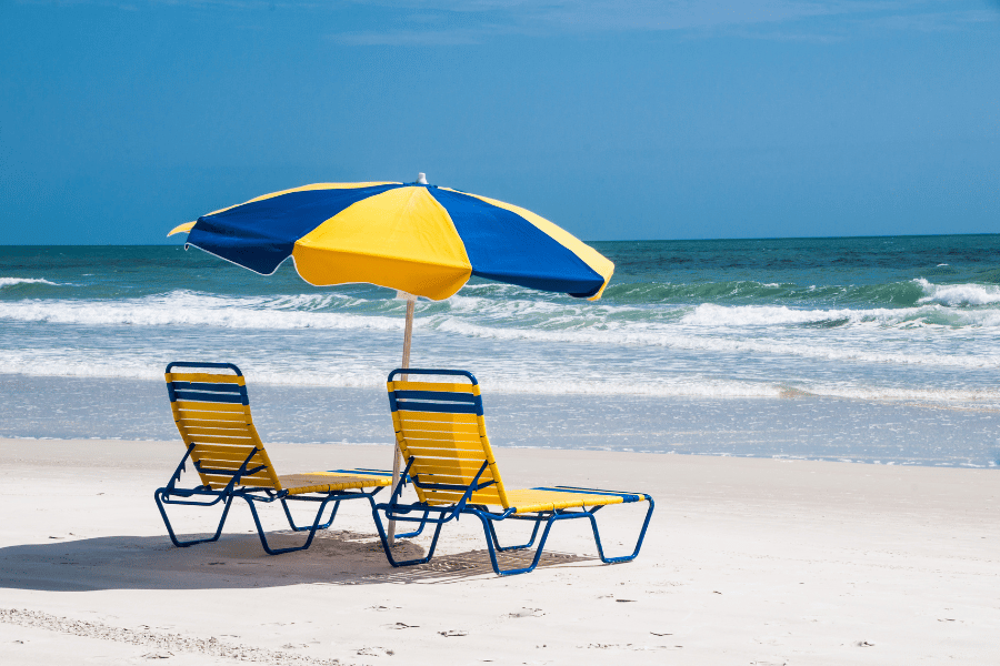 Two yellow and blue beach chairs with matching umbrella on the beach