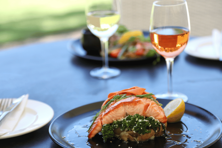 Image of a salmon entree with glass of wine