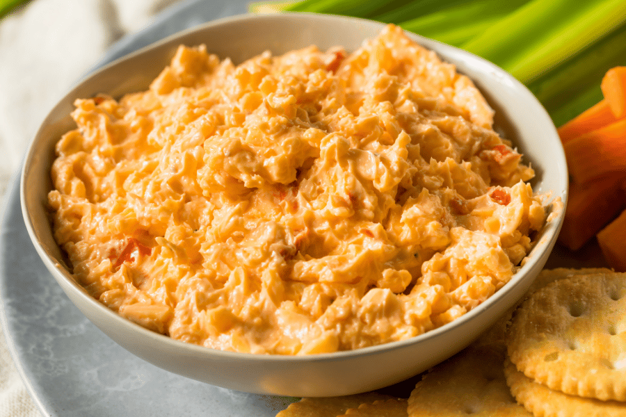 bowl of pimento cheese with crackers, carrots, and celery