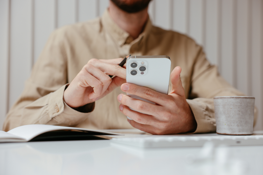 Using an Iphone next to a cup and notebook