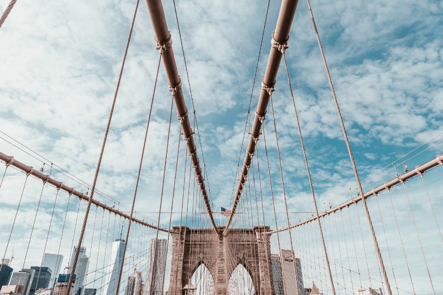 The Brooklyn Bridge on a cloudy day with the American flag