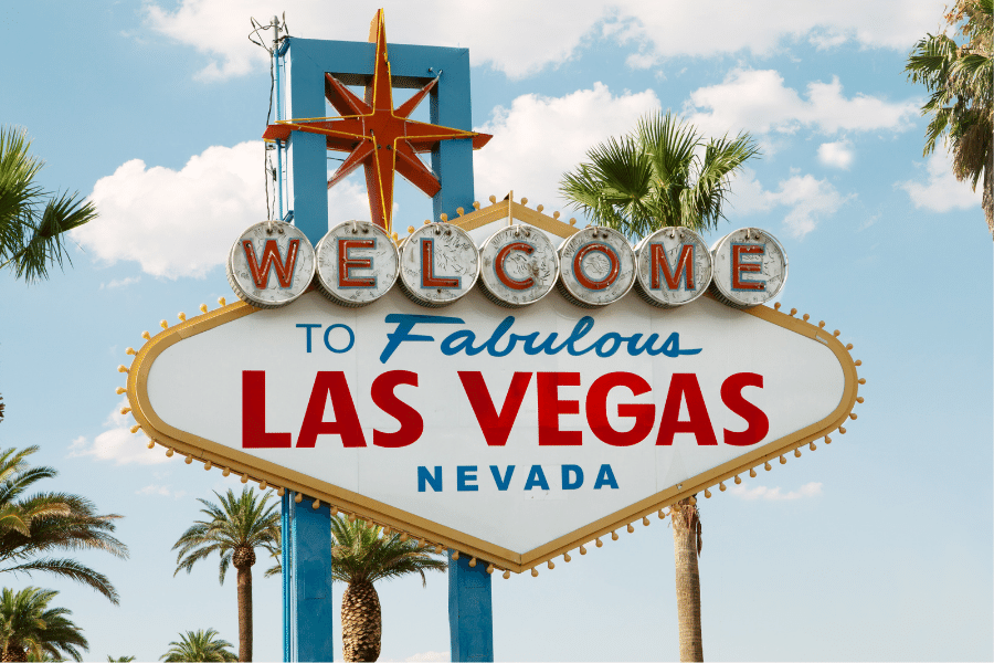 The infamous Welcome to Las Vegas sign during the day surrounded by palm trees 