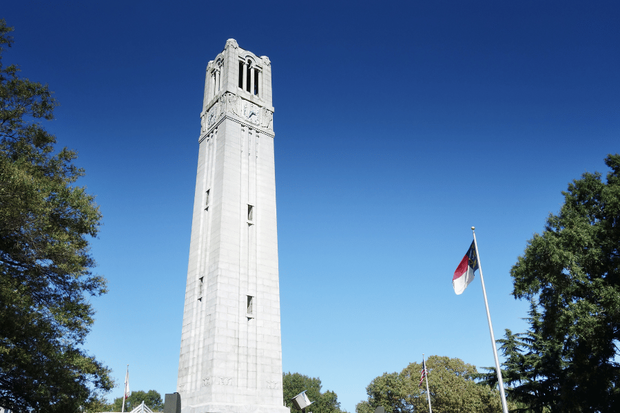 NC State clock tower on campus with NC flag 