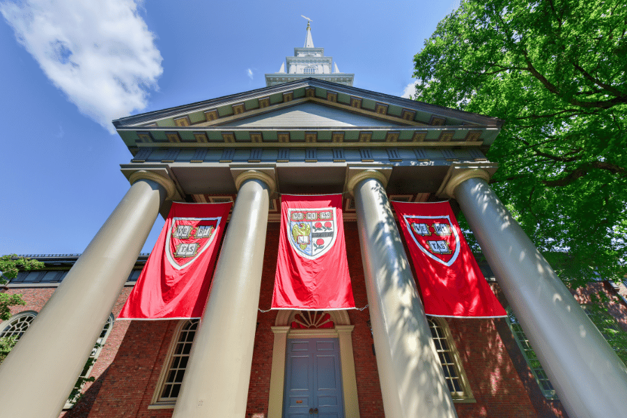 Harvard University buildings with Harvard flags on a sunny day