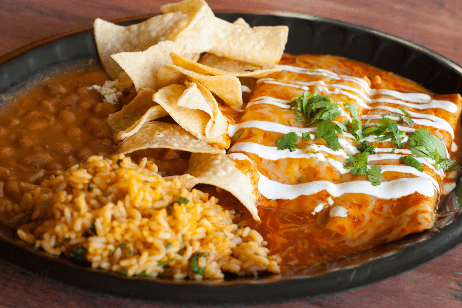 Plate of delicious enchiladas, chips, rice, and beans 