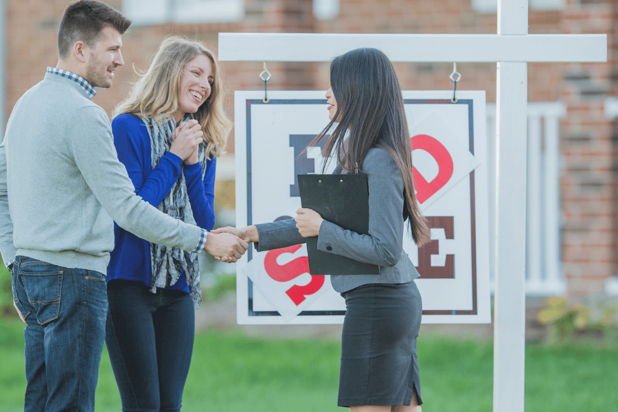 Buying a home with an agent in front of the for sale sign in the yard