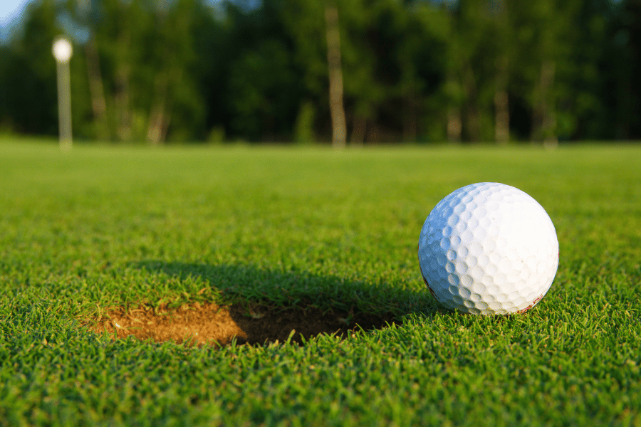 golf ball on golf course with fresh green grass near the cup