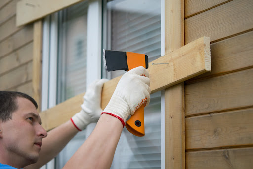 A person boarding up the windows of their home to protect against natural disasters due to climate change.