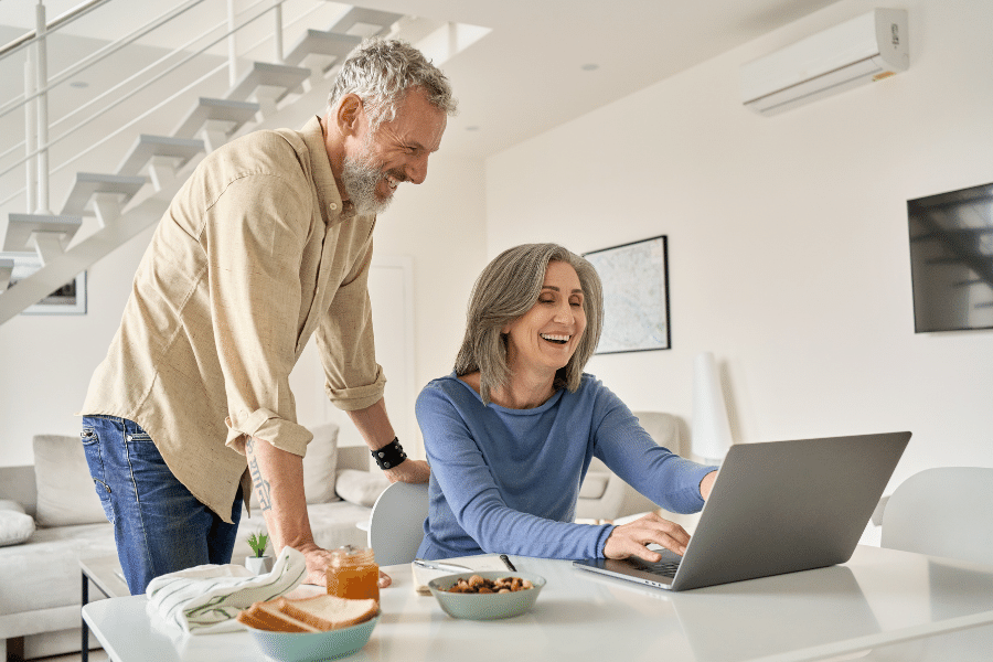 A happy couple talking and looking at a computer 