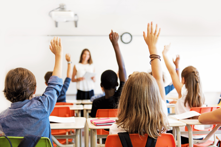 children in school raising hands
