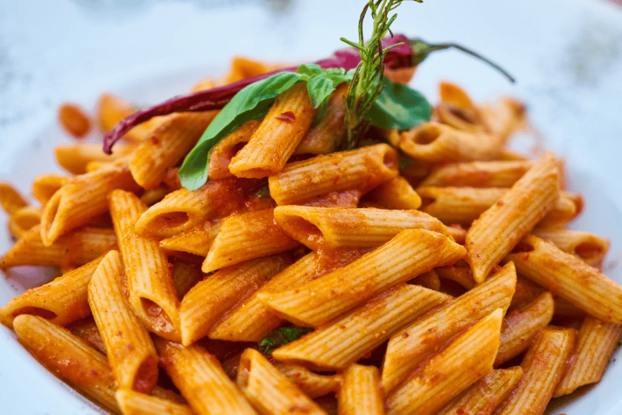 penne pasta cooked in red sauce with basil