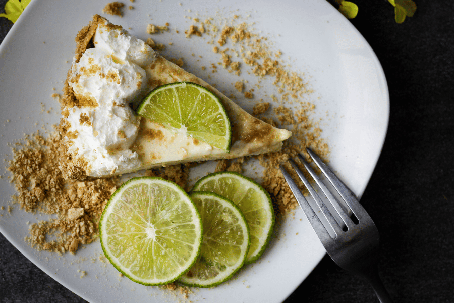 Delicious slice of key lime pie on a plate with key lime slices and graham crackers 