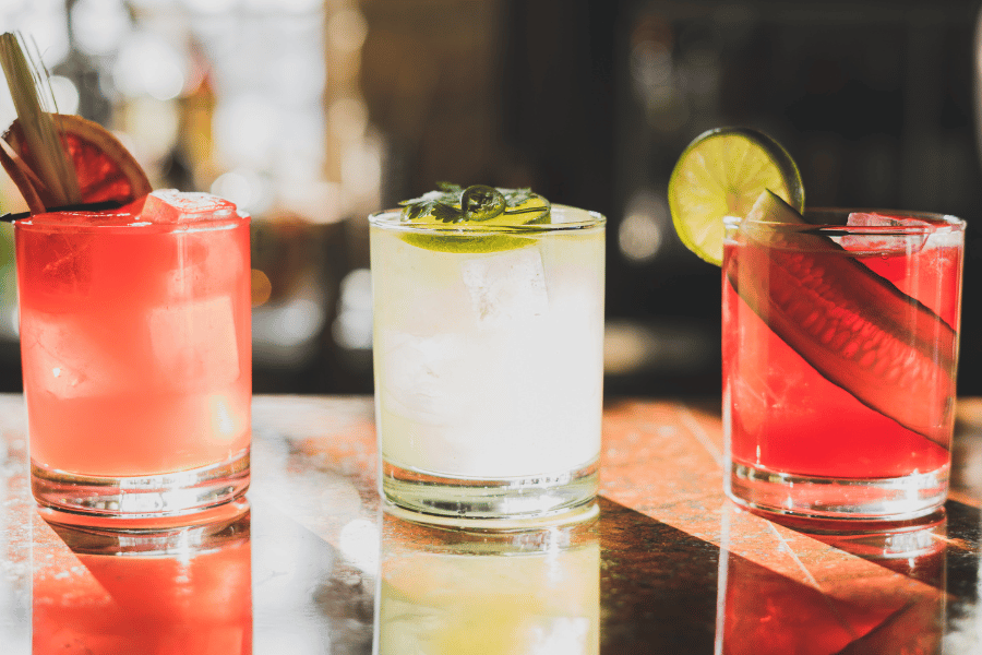 three margaritas with garnishes on a table 