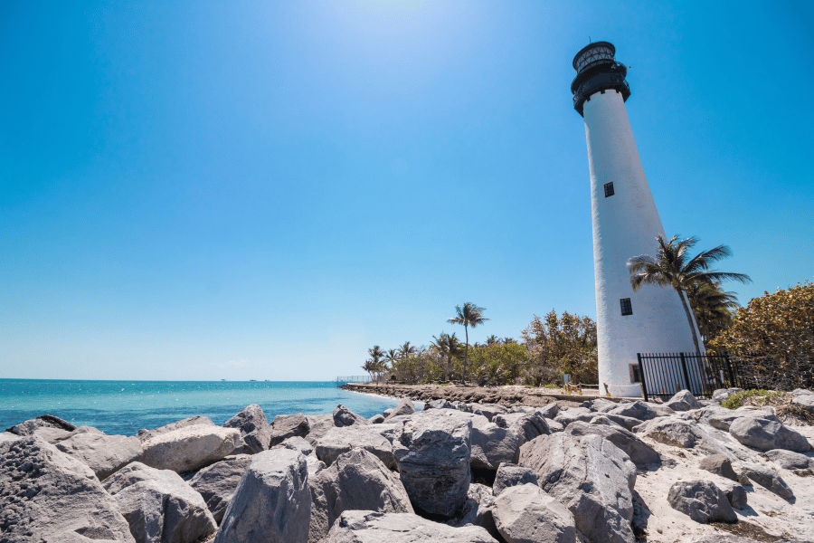 Cape Florida Lighthouse near the water, rocks, and palm trees