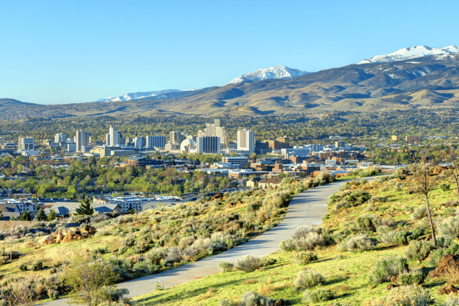 Buildings in Reno, Nevada on a sunny day with clear blue skies and snow capped mountains in the background