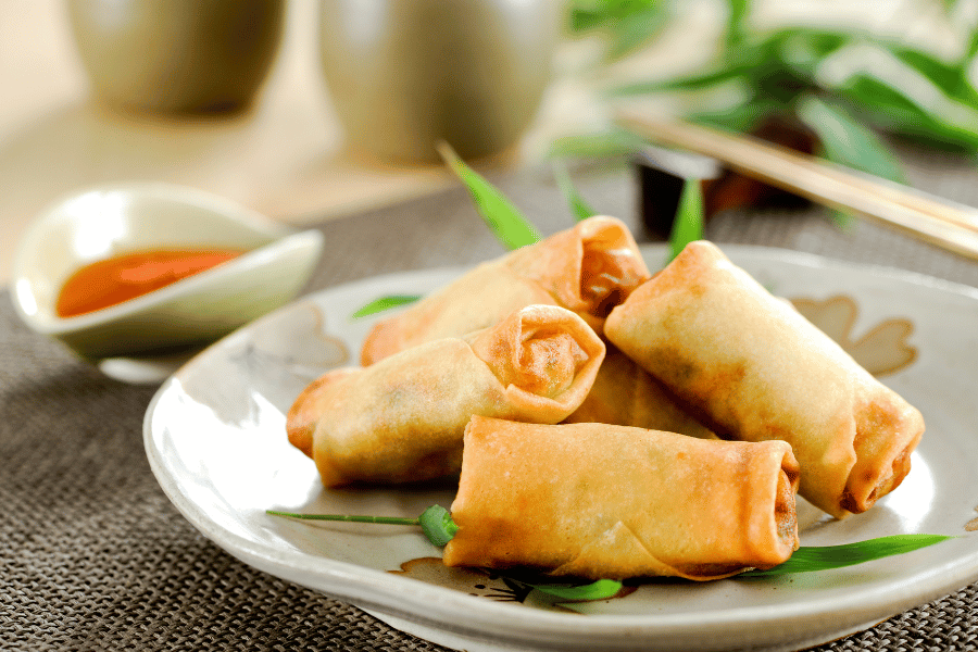 spring rolls on a plate with a bowl of sauce 