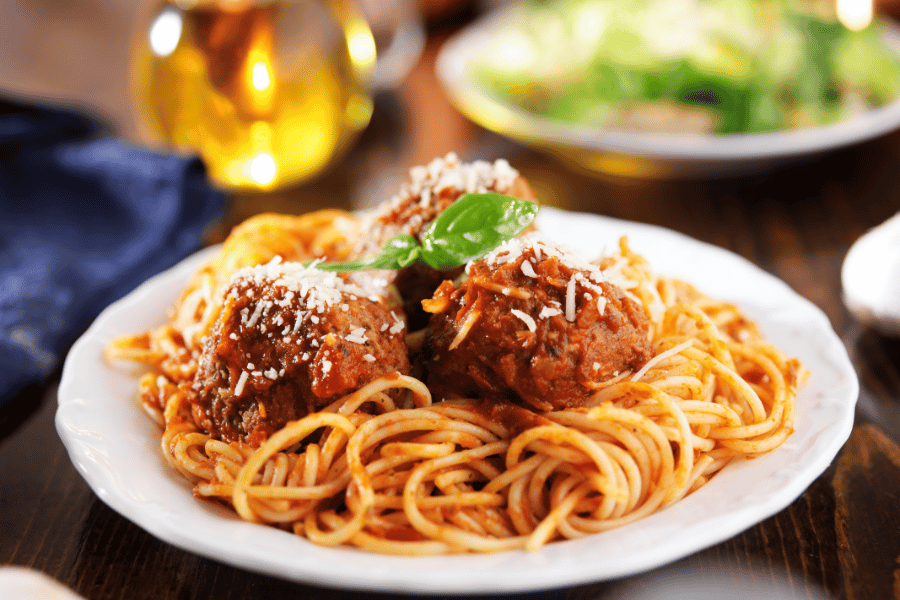 white bowl of spaghetti and meatballs 