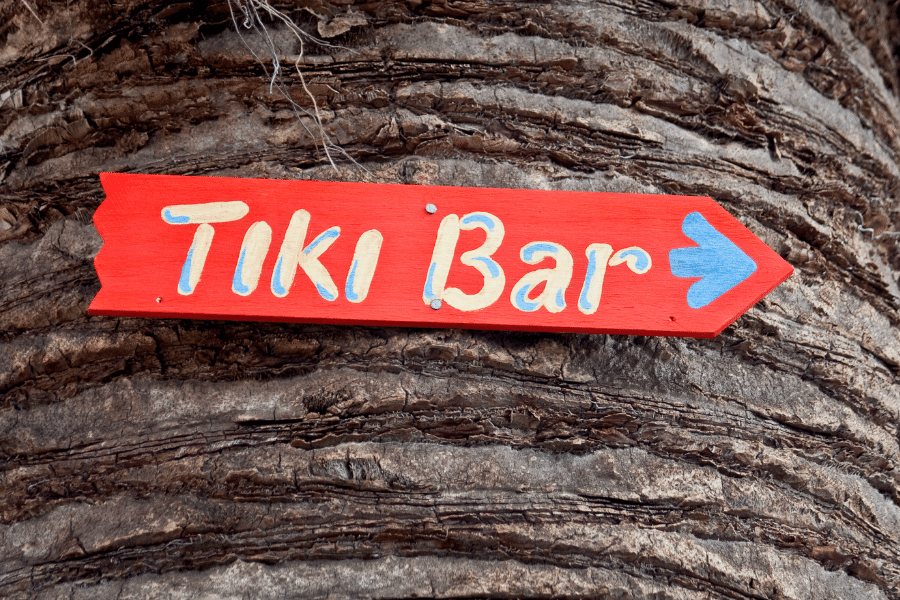 red and blue tiki bar sign on palm tree trunk
