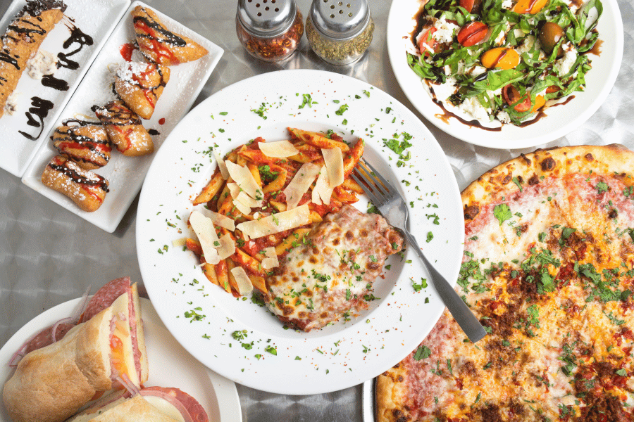 spread of Italian food on a table with pizza, pasta, and salad, and 