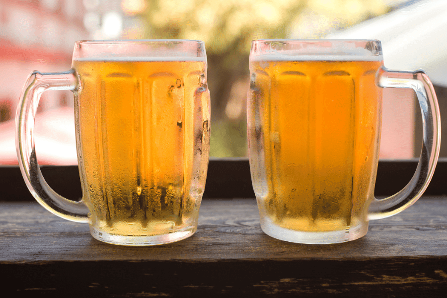 two glasses of cold beer on a wood table 