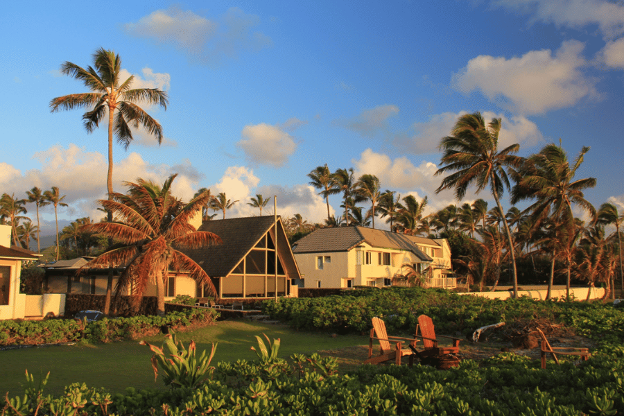 Oceanfront Home in Oahu, HI at sunset with palm trees and 