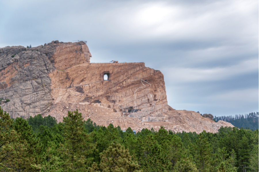 Crazy Horse Memorial in South Dakota on a cloudy day with greens trees 
