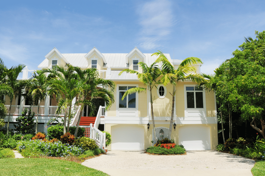 Yellow home with front porch on Sanibel Island surrounded by palm trees