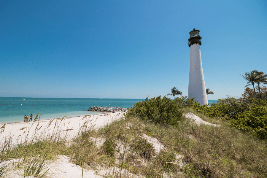 Cape Florida Lighthouse on the beach with crystal blue water and palm trees